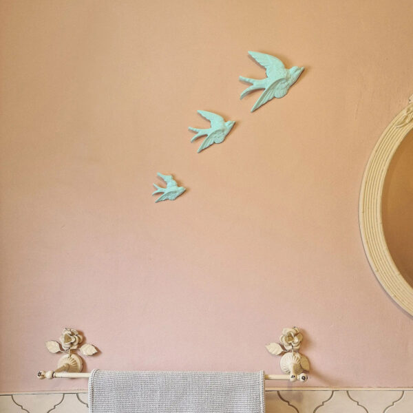 A set of three ceramic blue swallows on a bathroom wall