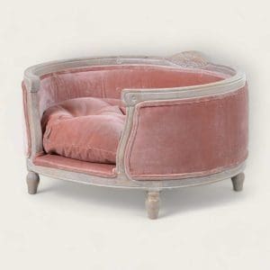 Elegant pink circular dog bed with a cushioned pillow and a charming vintage design, made from solid wood.