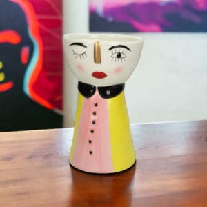 A ceramic vase with a winking face on a table