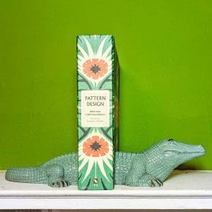 Vibrant green Crocodile bookends named Clovis, positioned to support books on a shelf.