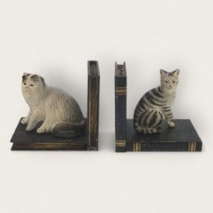 Elegant cat bookends with detailed markings, nestled among classic literature.